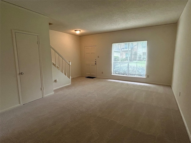 interior space with a textured ceiling and light colored carpet