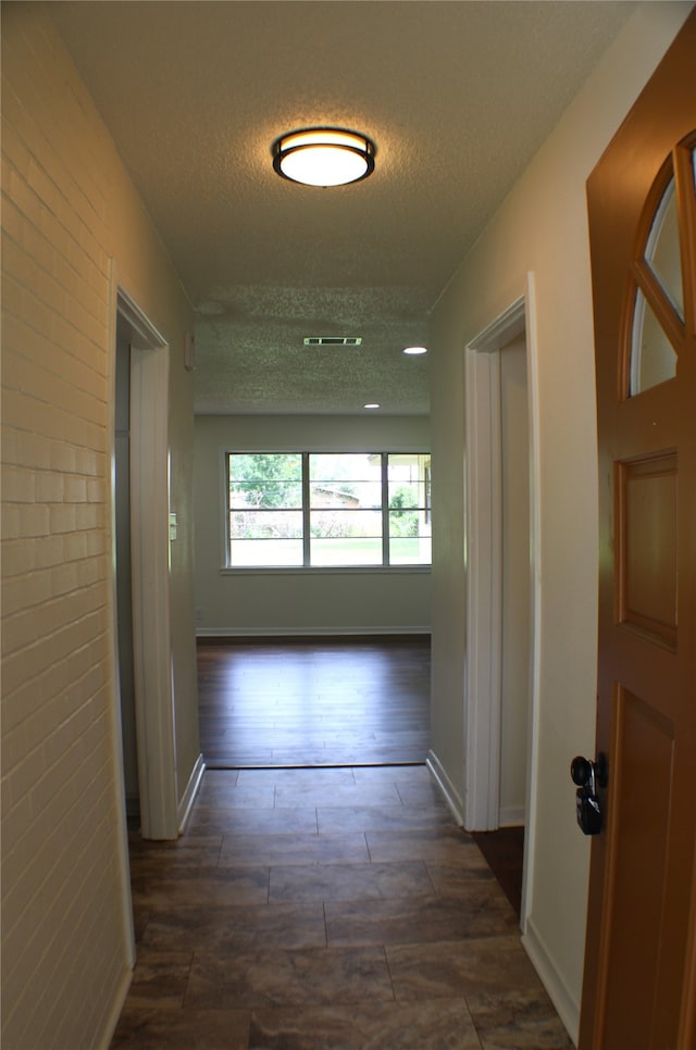 hall with dark hardwood / wood-style flooring and a textured ceiling