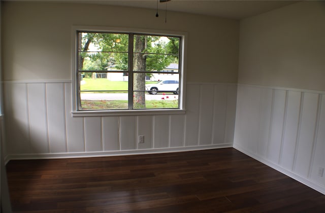 spare room with a wealth of natural light and dark wood-type flooring