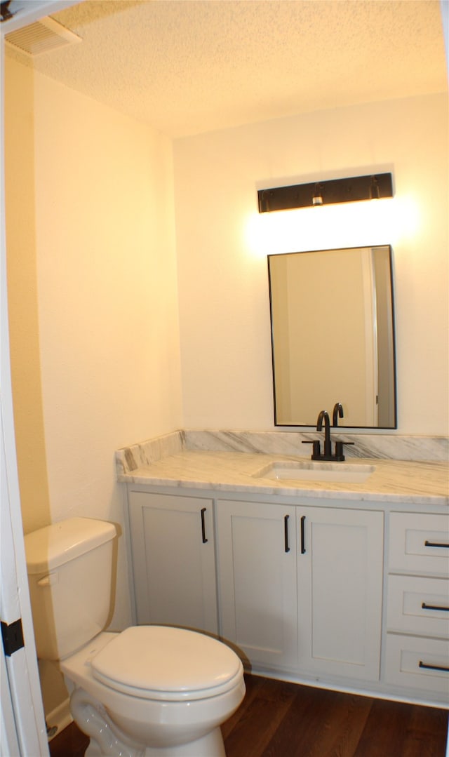 bathroom with a textured ceiling, hardwood / wood-style flooring, toilet, and vanity