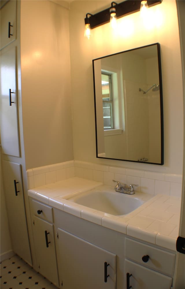 bathroom featuring tile flooring, vanity, and tasteful backsplash