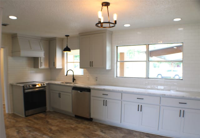 kitchen featuring custom range hood, appliances with stainless steel finishes, backsplash, pendant lighting, and sink