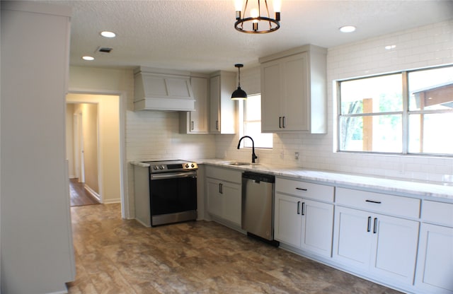 kitchen with appliances with stainless steel finishes, premium range hood, pendant lighting, sink, and tasteful backsplash