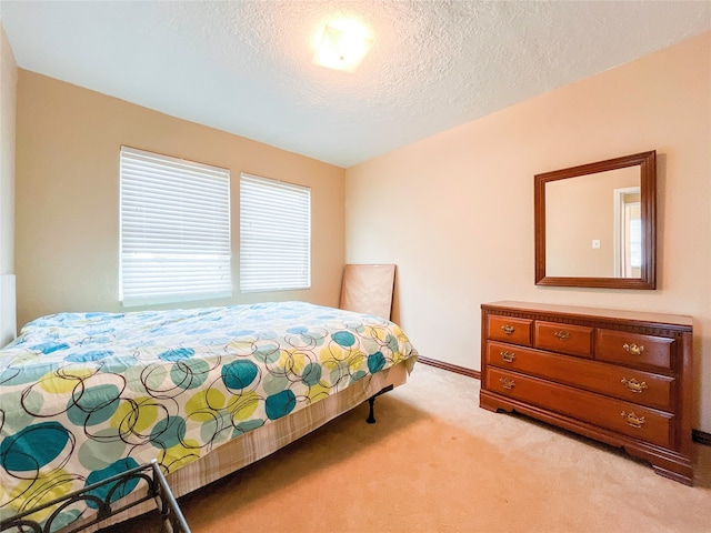 bedroom with multiple windows, a textured ceiling, and light carpet