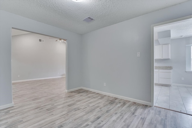 spare room with light hardwood / wood-style flooring, a textured ceiling, and ceiling fan