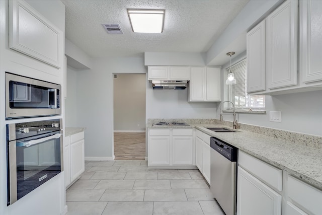 kitchen with hanging light fixtures, sink, white cabinetry, appliances with stainless steel finishes, and a textured ceiling