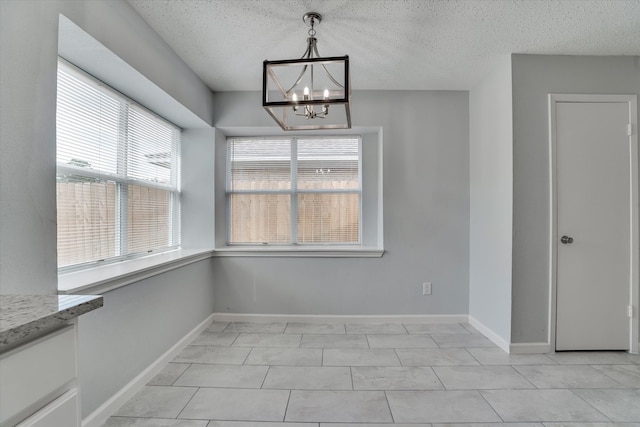 unfurnished dining area featuring a notable chandelier, a textured ceiling, and light tile patterned flooring