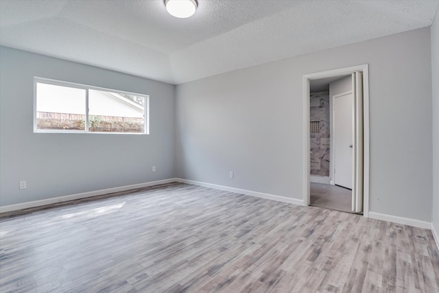 spare room featuring light hardwood / wood-style flooring and a textured ceiling