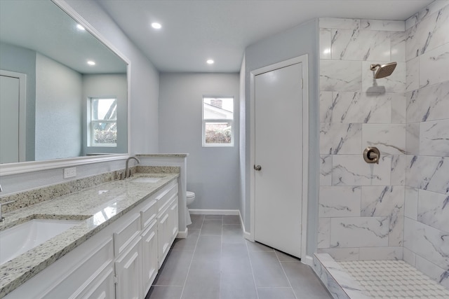 bathroom featuring toilet, vanity, a tile shower, and tile patterned flooring