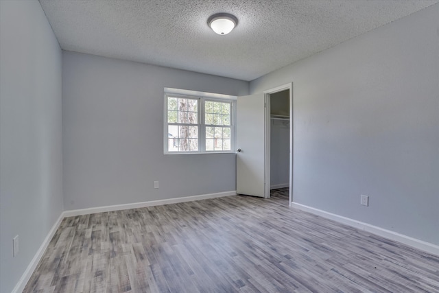 unfurnished bedroom with light hardwood / wood-style floors, a closet, and a textured ceiling