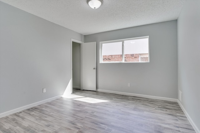 unfurnished room with a textured ceiling and light hardwood / wood-style floors