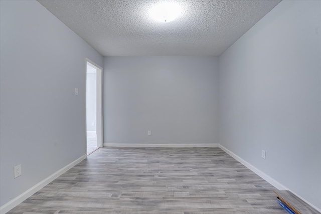 empty room with light hardwood / wood-style flooring and a textured ceiling