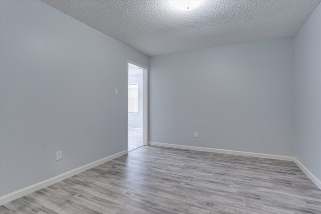 spare room featuring light hardwood / wood-style floors and a textured ceiling