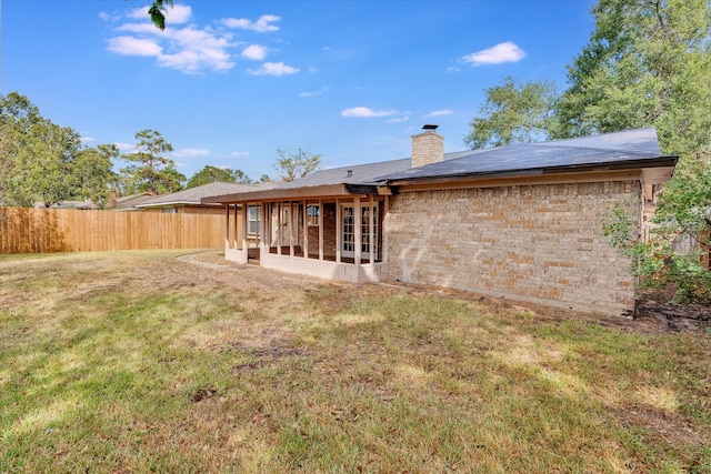 rear view of property featuring a yard and a sunroom