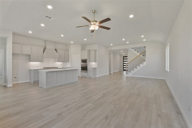 unfurnished living room with light wood-type flooring, ceiling fan, and sink