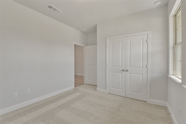 unfurnished bedroom with light carpet and a closet