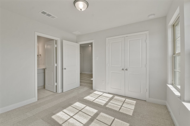 unfurnished bedroom featuring light carpet, a closet, and multiple windows