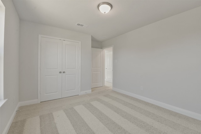 unfurnished bedroom with light colored carpet and a closet