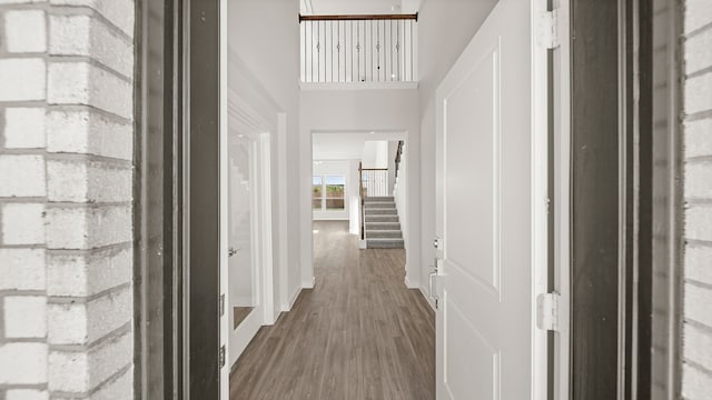 corridor featuring a towering ceiling and dark wood-type flooring