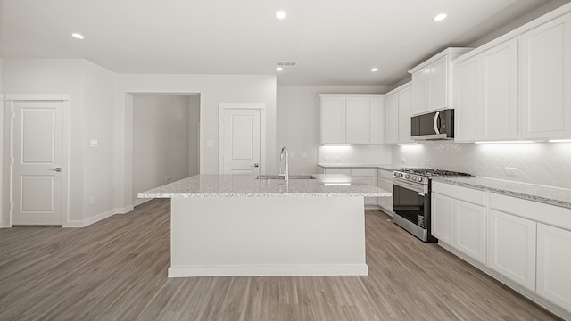 kitchen with a kitchen island with sink, sink, stainless steel appliances, and light wood-type flooring