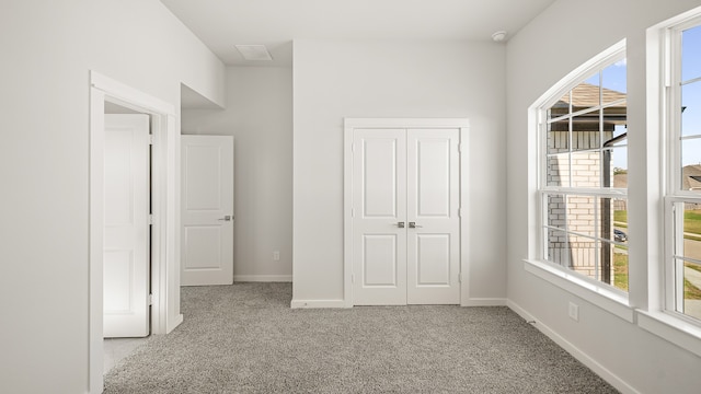 unfurnished bedroom with a closet, multiple windows, and light colored carpet