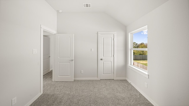 unfurnished bedroom with carpet flooring and vaulted ceiling