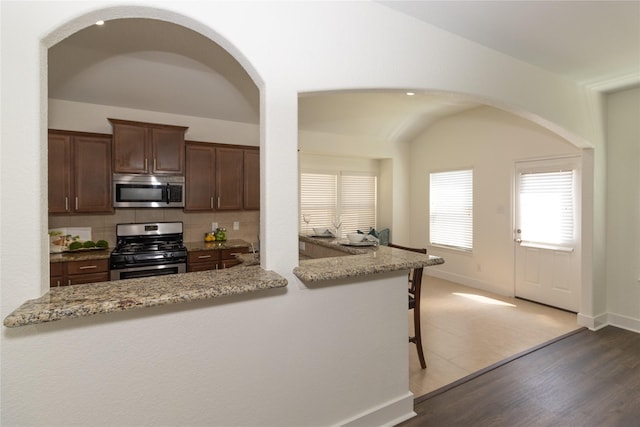 kitchen featuring light stone countertops, appliances with stainless steel finishes, backsplash, and dark hardwood / wood-style flooring