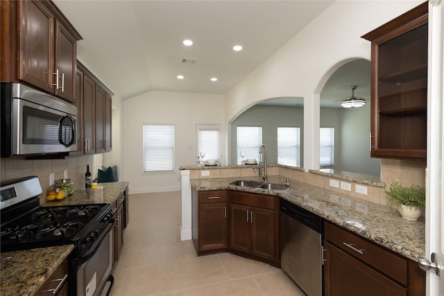 kitchen with light stone counters, vaulted ceiling, stainless steel appliances, decorative backsplash, and sink