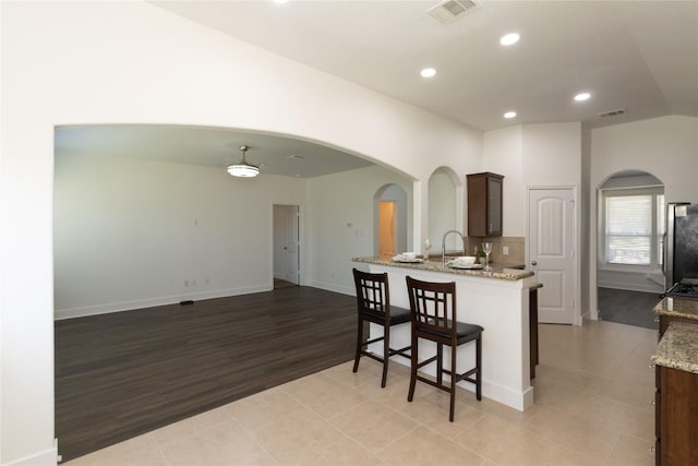 kitchen with light tile patterned floors, light stone counters, and stainless steel fridge