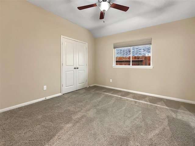 unfurnished bedroom with ceiling fan, a closet, carpet, and lofted ceiling