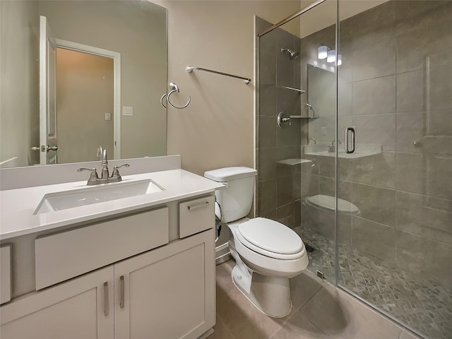 bathroom with tile patterned floors, vanity, toilet, and a shower with shower door