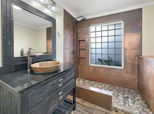 bathroom with a tile shower, vanity, wood-type flooring, and ornamental molding