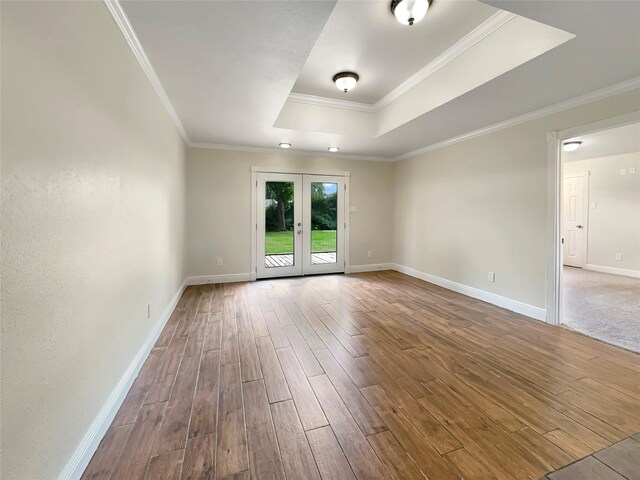 unfurnished room with wood-type flooring, ornamental molding, french doors, and a raised ceiling