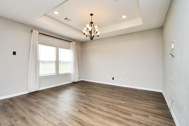 spare room with dark wood-type flooring, a notable chandelier, and a tray ceiling