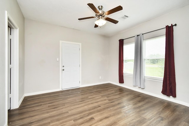 spare room with dark wood-type flooring, a healthy amount of sunlight, and ceiling fan