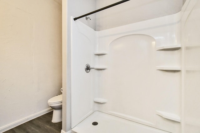 bathroom featuring toilet, a shower, and hardwood / wood-style flooring