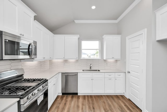 kitchen with sink, crown molding, decorative backsplash, white cabinets, and appliances with stainless steel finishes