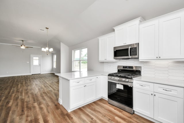 kitchen with kitchen peninsula, appliances with stainless steel finishes, decorative backsplash, white cabinets, and light hardwood / wood-style floors