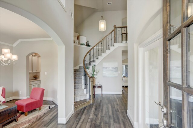 entryway with a notable chandelier, dark hardwood / wood-style flooring, lofted ceiling, and ornamental molding