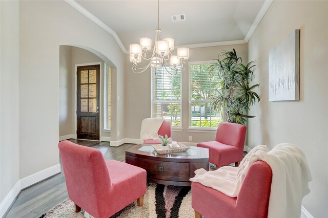 living area with hardwood / wood-style flooring, a chandelier, crown molding, and vaulted ceiling