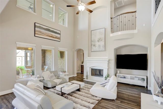 living room with dark hardwood / wood-style flooring, a towering ceiling, and ceiling fan