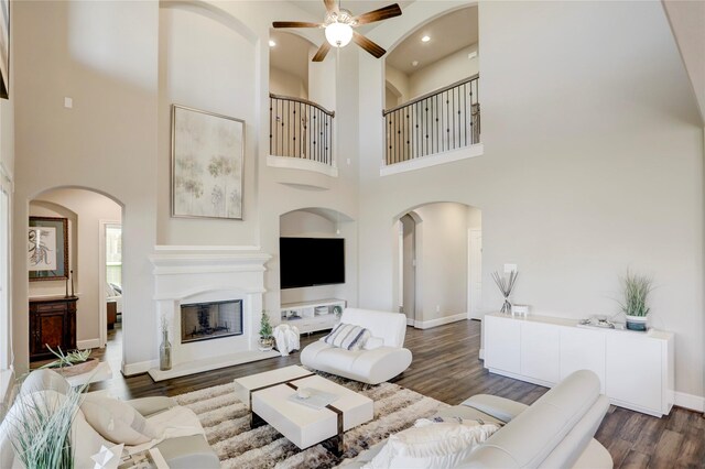 living room featuring ceiling fan, dark hardwood / wood-style floors, and a high ceiling