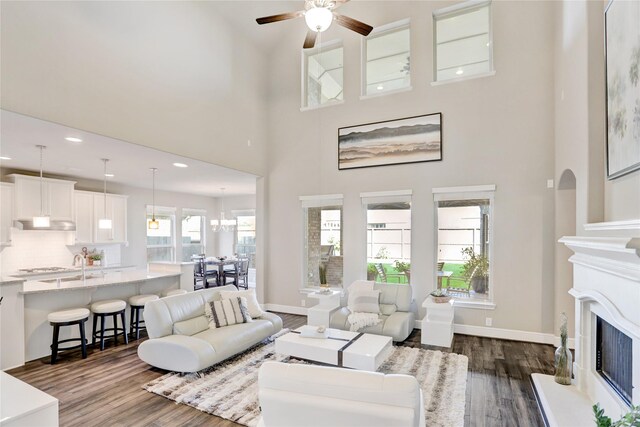 living room featuring ceiling fan, a towering ceiling, and dark wood-type flooring