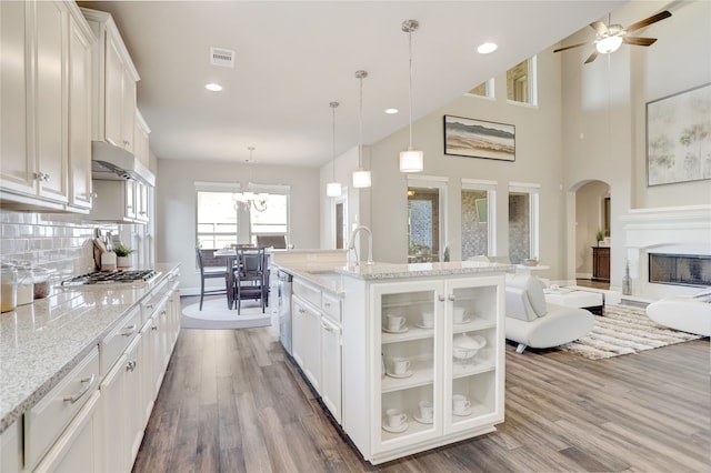 kitchen featuring backsplash, white cabinetry, an island with sink, and hanging light fixtures