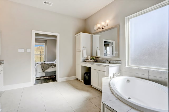 bathroom with a bathing tub, vanity, and tile patterned flooring