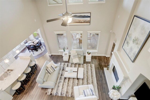 living room with a healthy amount of sunlight, ceiling fan, wood-type flooring, and a high ceiling