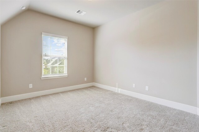 carpeted empty room featuring vaulted ceiling