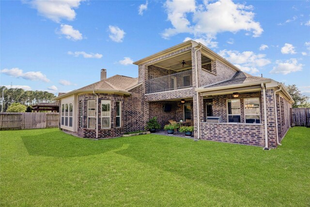 back of property with ceiling fan, a yard, and a balcony