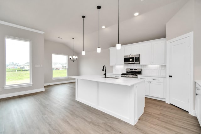 kitchen with appliances with stainless steel finishes, a center island with sink, vaulted ceiling, and sink