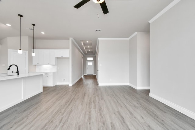 unfurnished living room with ceiling fan, light hardwood / wood-style flooring, crown molding, and sink